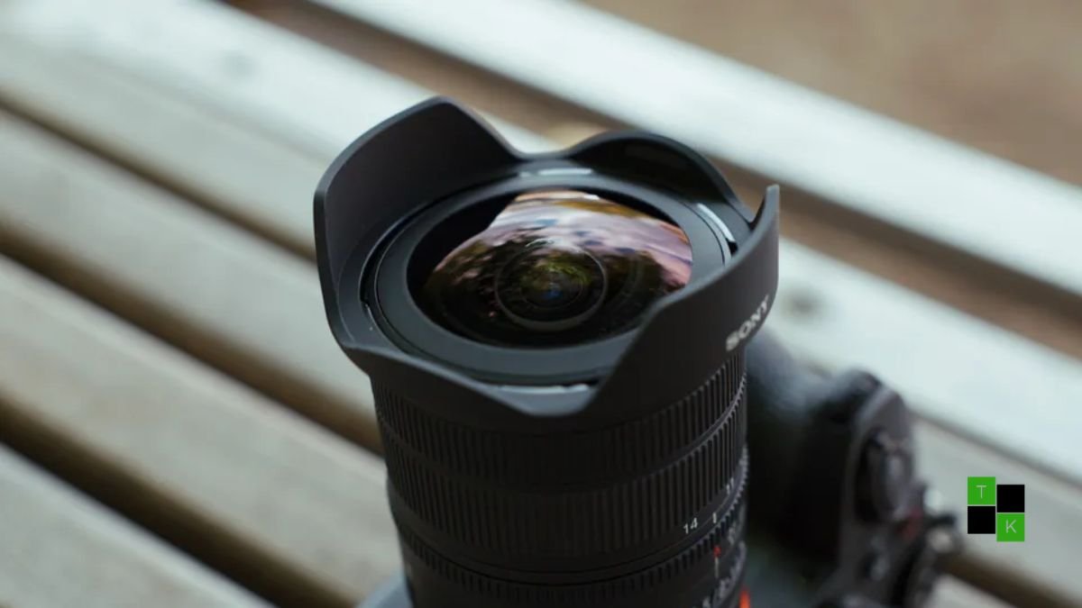 The compact Sony FE 8-14mm F3.5 G Fisheye zoom lens resting on a camera bag beside a Sony Alpha 7 mirrorless camera.