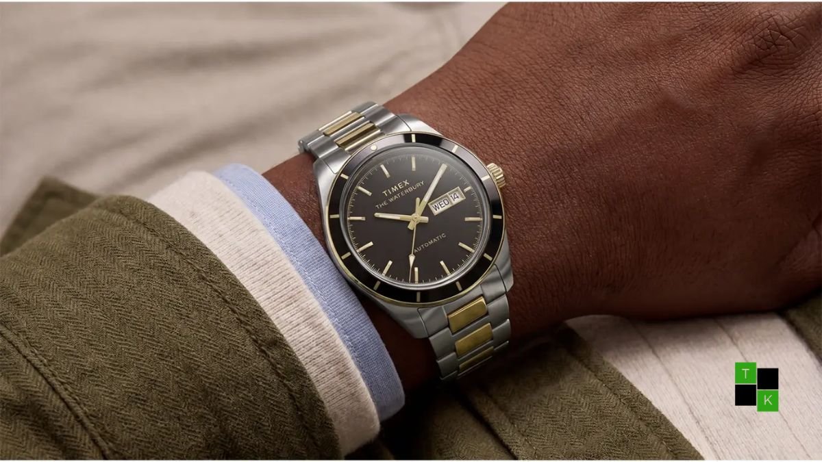 Three Timex Waterbury Heritage automatic watches resting on a leather tray showing the blue Day-Date, two-tone black, and maroon-black bezel GMT models.