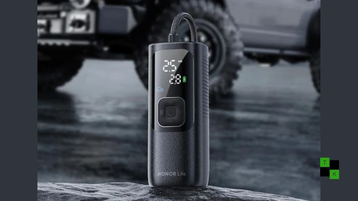 The Honor Life Air Pump Lite portable air compressor resting on clean tarmac next to a car wheel showing its digital pressure screen.
