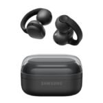 A pair of Samsung Galaxy Buds On clip-style open earbuds in Phantom Black shown resting on a desk next to their pebble charging case.