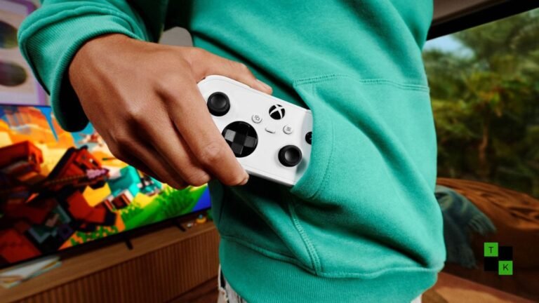 The compact Xbox Nano Controller in Robot White and Carbon Black resting on an executive desk next to a smartphone displaying cloud gaming.